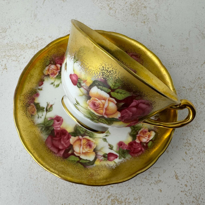 Front view of Royal Chelsea Golden Roses teacup resting on its side on matching saucer