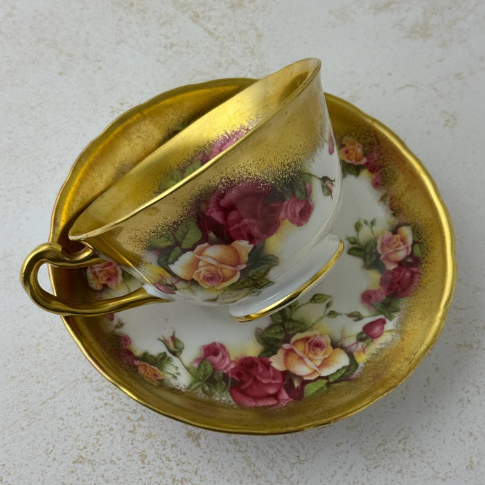 Back view of Royal Chelsea Golden Roses teacup resting on its side on matching saucer