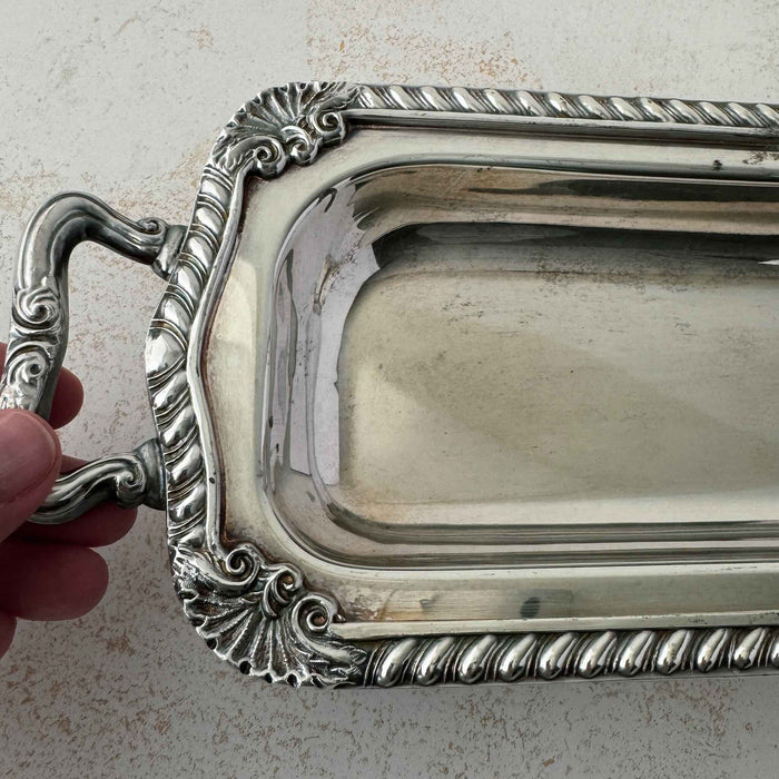 Close up of vintage silverplate rectangular serving tray with hand touching handle