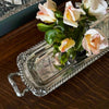 Vintage silverplate rectangular serving tray with a vase of pink and white roses on a wooden surface