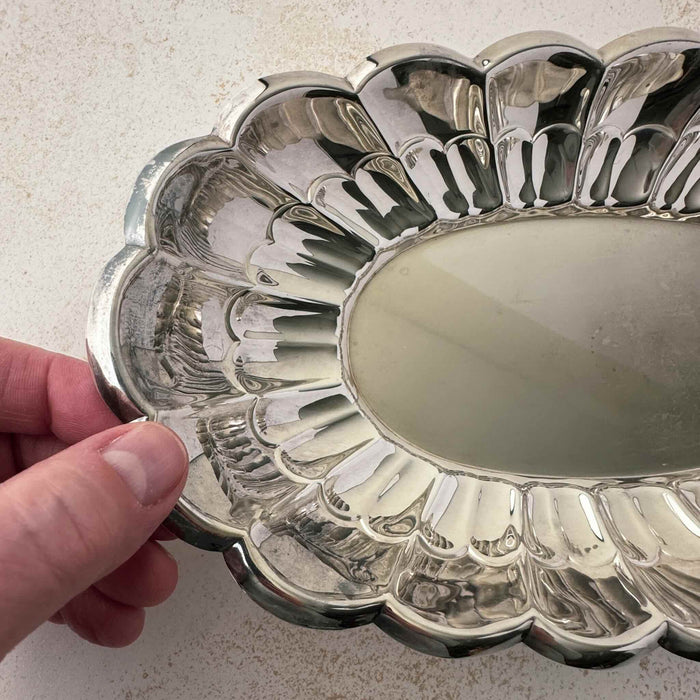 Close-up view of vintage Towle silverplate oval bread tray with fingers holding the scalloped rim