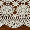 Close-up of white crochet table runner over dark wood, showing large circular medallions, smaller connecting motifs, openwork, and scalloped border.