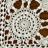 Detailed close-up of a large circular crochet medallion with smaller openwork motifs surrounding it against dark wood.