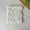 Overhead view of the neatly folded white crochet table runner, showing repeating circular medallions, openwork, and scalloped edges.