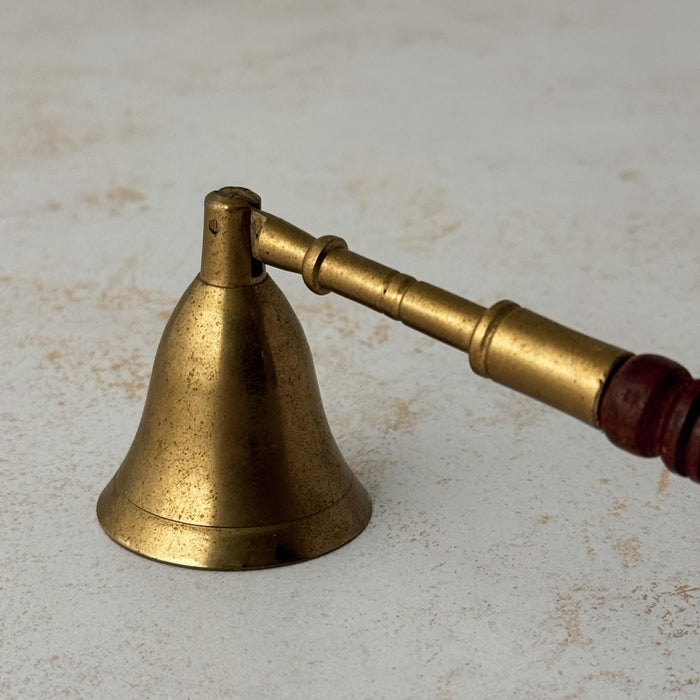Close-up view of vintage brass candle snuffer with turned wood handle