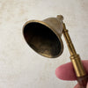 View of interior of vintage brass candle snuffer with turned wood handle held by a hand