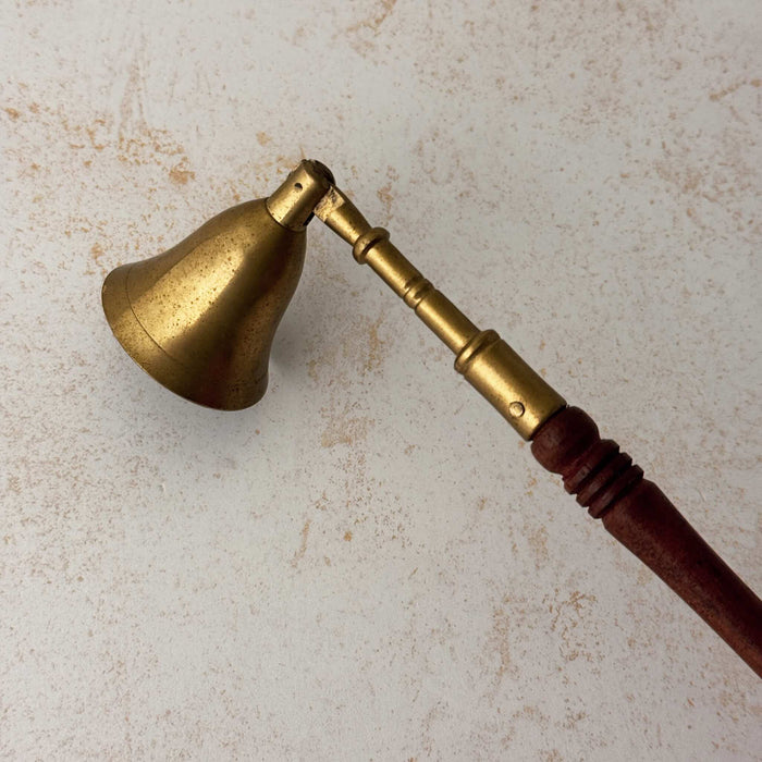 Side view of vintage brass candle snuffer with turned wood handle