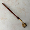 Top down view of vintage brass candle snuffer with turned wood handle