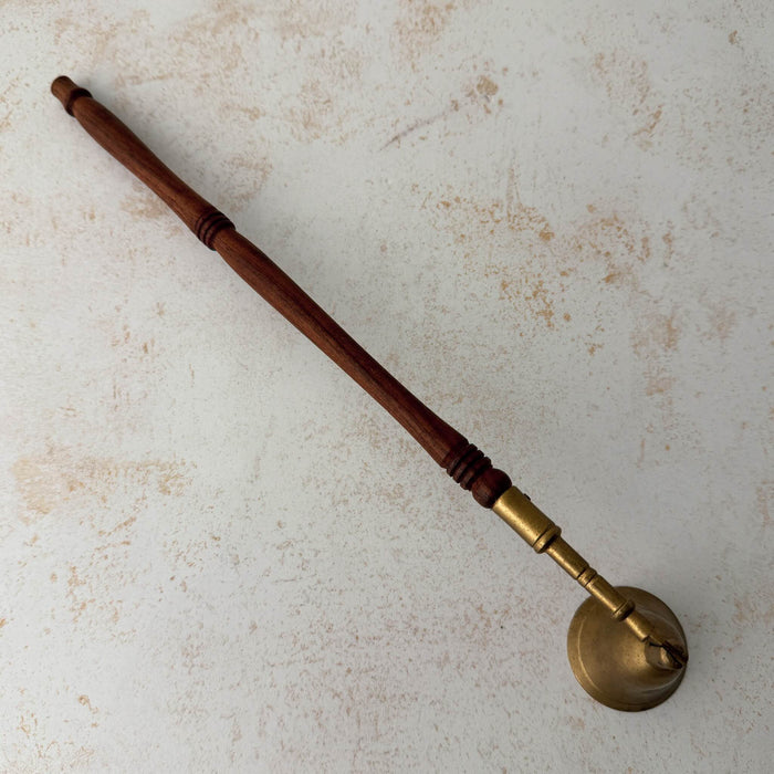 Top down view of vintage brass candle snuffer with turned wood handle
