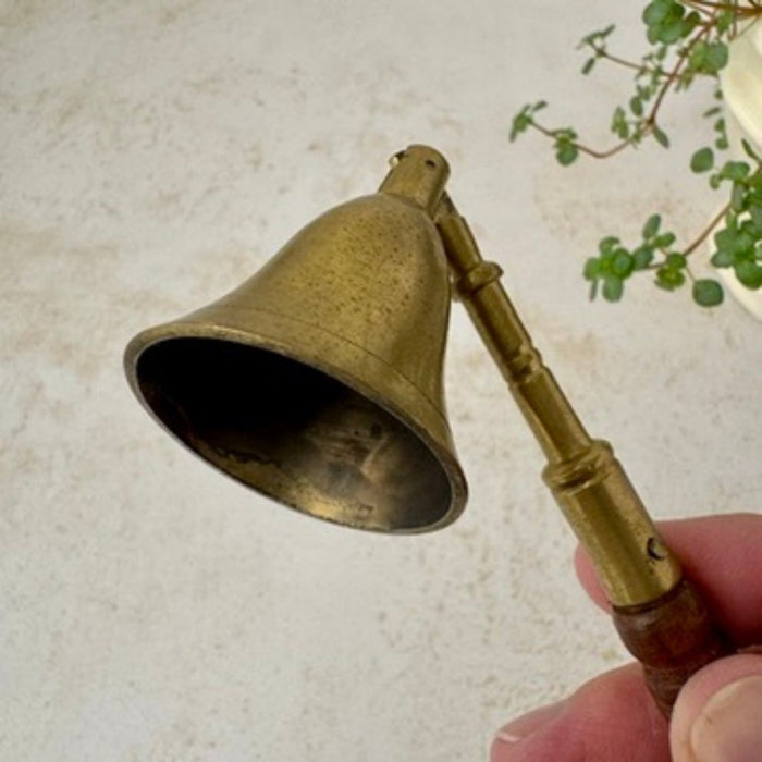 Close-up of vintage brass candle snuffer showing inside of bell-shaped snuffer and aged brass finish