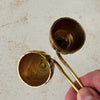 Top down view of interiors of vintage brass candle snuffers with hand holding twisted handles