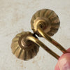 Top down view of tops of vintage brass candle snuffers with hand holding twisted handles