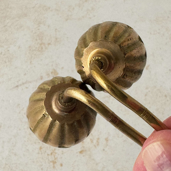 Top down view of tops of vintage brass candle snuffers with hand holding twisted handles