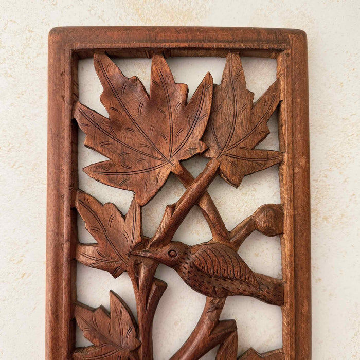 Close-up view of top of vintage hand-carved wooden panel showing bird and foliage
