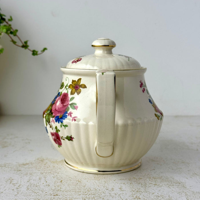 Handle view of vintage Sadler teapot showing its flat-topped angular handle, ribbed body, floral decoration, and gold detailing.