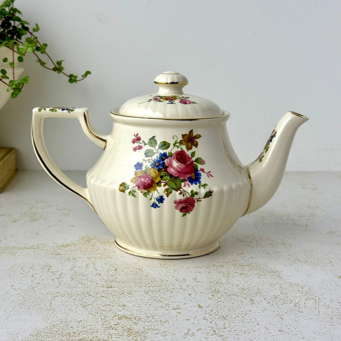 Opposite side of vintage Sadler teapot with pink rose floral bouquet, ribbed cream body, long spout, and gold-trimmed handle.