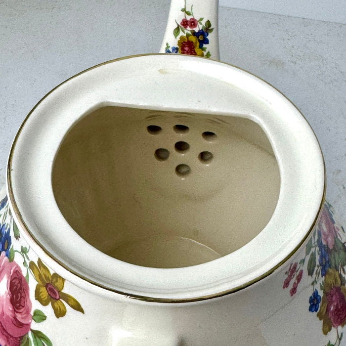 Close-up inside vintage Sadler teapot showing the cream-colored interior and strainer holes at the base of the spout.