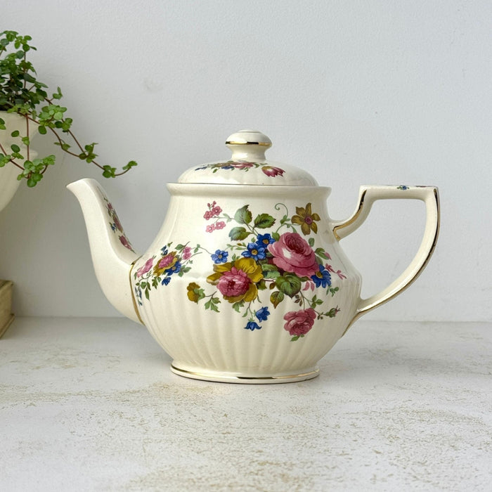 Vintage Sadler England teapot with pink, blue, and golden-brown floral bouquets, ribbed cream ceramic body, and gold trim.