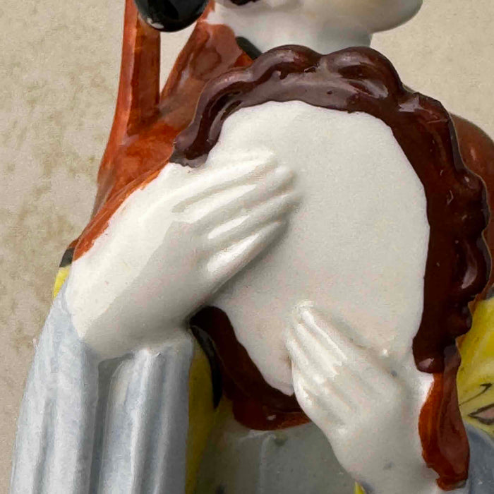 Close-up of the back of the mirror held gently by the hands of the vintage Chinese porcelain woman figurine showing the graceful fingers