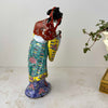 Rear three-quarter view of vintage Chinese porcelain court lady figurine showing the back of her robe and dangling red hair ribbons 