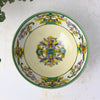Overhead view of the cream-colored bowl showing a central bird motif surrounded by a decorative border of paired birds, pink flowers, green foliage, and yellow scrollwork.