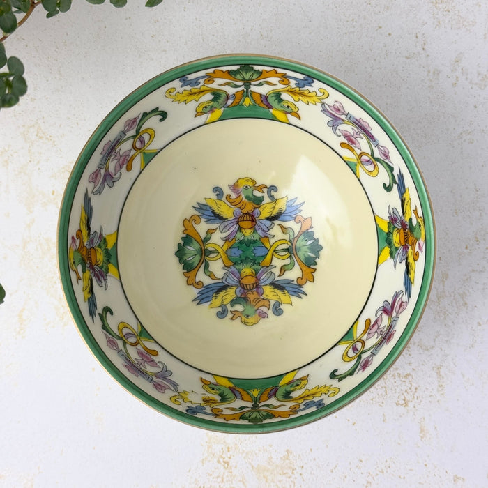 Overhead view of the cream-colored bowl showing a central bird motif surrounded by a decorative border of paired birds, pink flowers, green foliage, and yellow scrollwork.