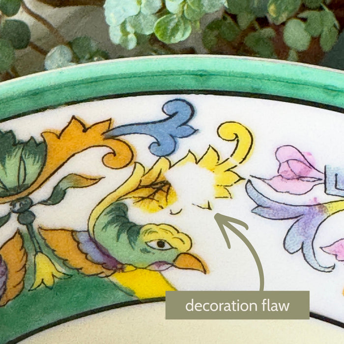 Close-up of a stylized bird and yellow floral decoration near the bowl's green rim, with an arrow identifying an area of incomplete decoration labeled "decoration flaw."