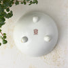 Underside of the white porcelain bowl showing three rounded feet and a red-brown Noritake maker's mark at the center.