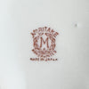 Close-up of the red-brown Noritake backstamp with a wreath surrounding the letter M and the words "Noritake," "Hand Painted," and "Made in Japan."