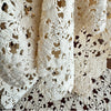 Close-up of the ecru crochet table runner draped in soft folds, showing the texture and openwork floral construction.