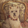 Close view of the needlepoint scene showing the white Westie wearing a red collar and seated on a patterned armchair.