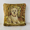 Square wool needlepoint pillow depicting a white Westie seated on an ornate armchair, surrounded by warm olive, gold, pink, plum, and tan details.