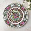 Vintage Chinese-style export porcelain plate with birds, peonies, butterflies, and longevity medallions in pink, turquoise green, and iron red, displayed on a white textured surface