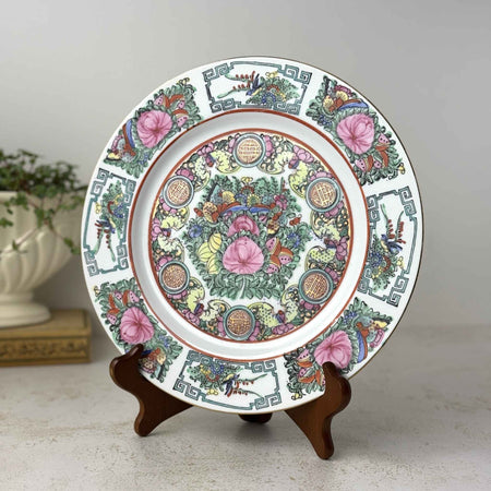 Vintage export porcelain plate with birds, peonies, butterflies, and longevity medallions in pink, turquoise green, and iron red styled in a plate stand