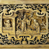 Close-up of central relief carving on vintage Chinese wood panel showing three robed figures in a courtyard scene with scrolling foliage in surrounding openwork
