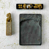 Close-up of vintage Chinese calligraphy  carved stone seal/chop, ink stick, and ink stone on a light surface