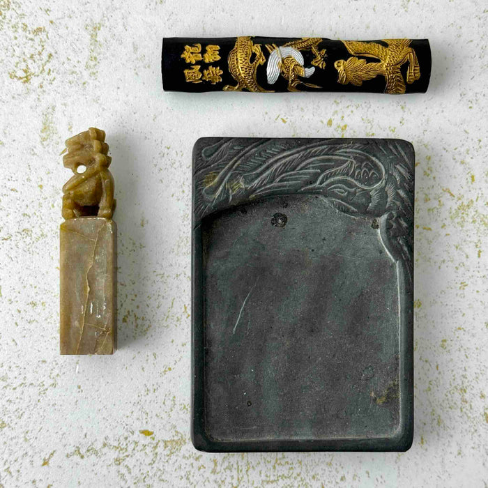 Close-up of vintage Chinese calligraphy  carved stone seal/chop, ink stick, and ink stone on a light surface