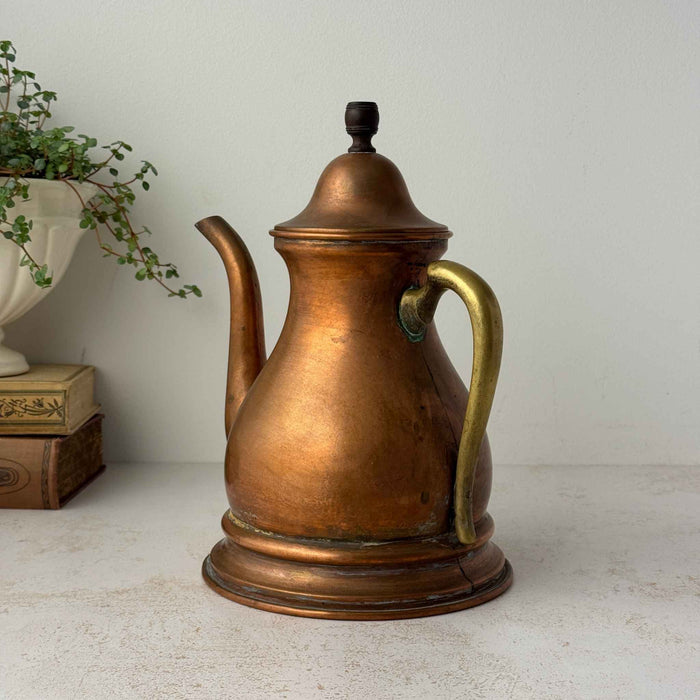 Vintage copper kettle with brass handle shown at a three-quarter angle, highlighting the curved body and aged copper patina.
