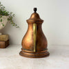 Rear view of vintage copper kettle showing the long brass handle and aged copper body.