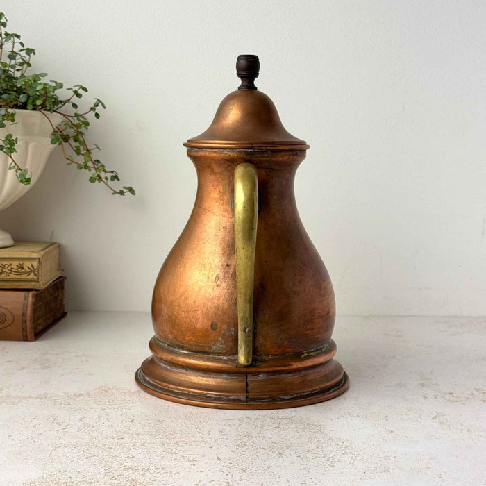 Rear view of vintage copper kettle showing the long brass handle and aged copper body.