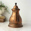 Spout view of vintage copper kettle showing the long narrow spout and rounded copper body.