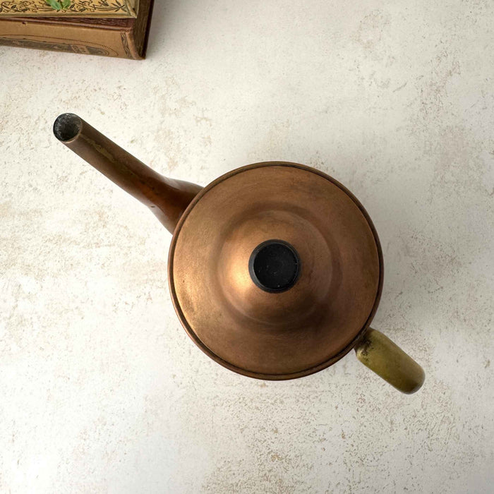 Top view of vintage copper kettle showing the domed lid, dark finial, brass handle, and long spout.