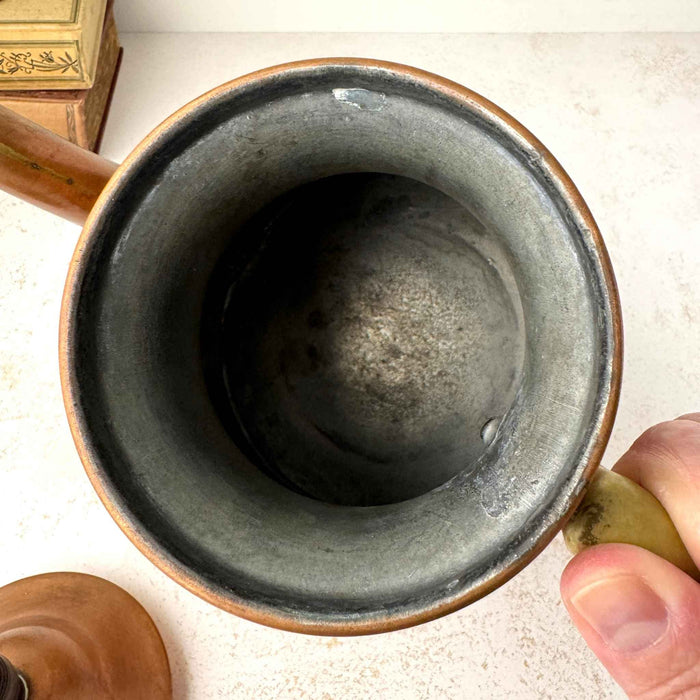 Interior of vintage copper kettle showing the gray metal lining and visible signs of age and use.