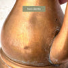 Close-up of two dents on the copper body near the spout of the vintage kettle.