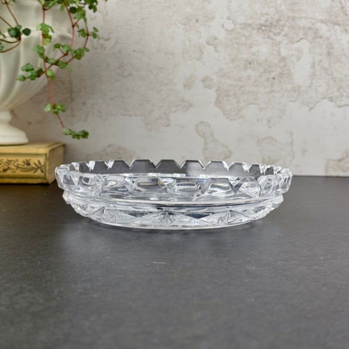 Side profile of the glass dish showing its low, shallow form, raised patterned sides, and evenly spaced notches around the rim.