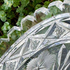 Detailed view of the glass dish's notched rim and geometric border, showing faceted edges, triangular patterns, and small star designs.