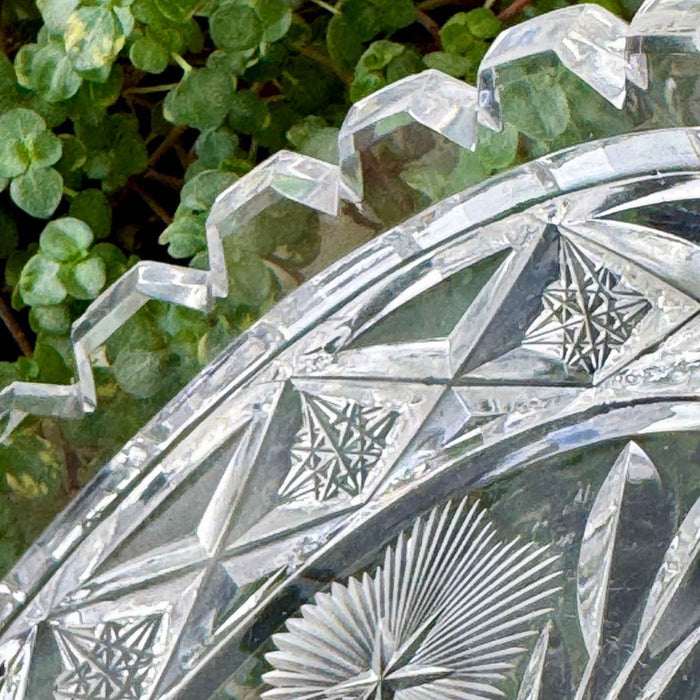 Detailed view of the glass dish's notched rim and geometric border, showing faceted edges, triangular patterns, and small star designs.