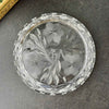 Underside of the round clear glass dish showing the three-flower design, pointed leaves, geometric border, and notched outer edge.