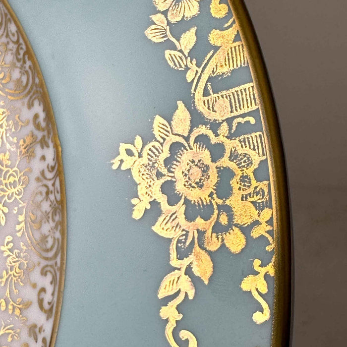 Close-up of ornate gold flowers, foliage and basket motifs on the turquoise blue porcelain rim.