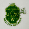 Close-up of the green JKW Fine Porcelain Western Germany shield mark partially covering a Rosenthal mark.